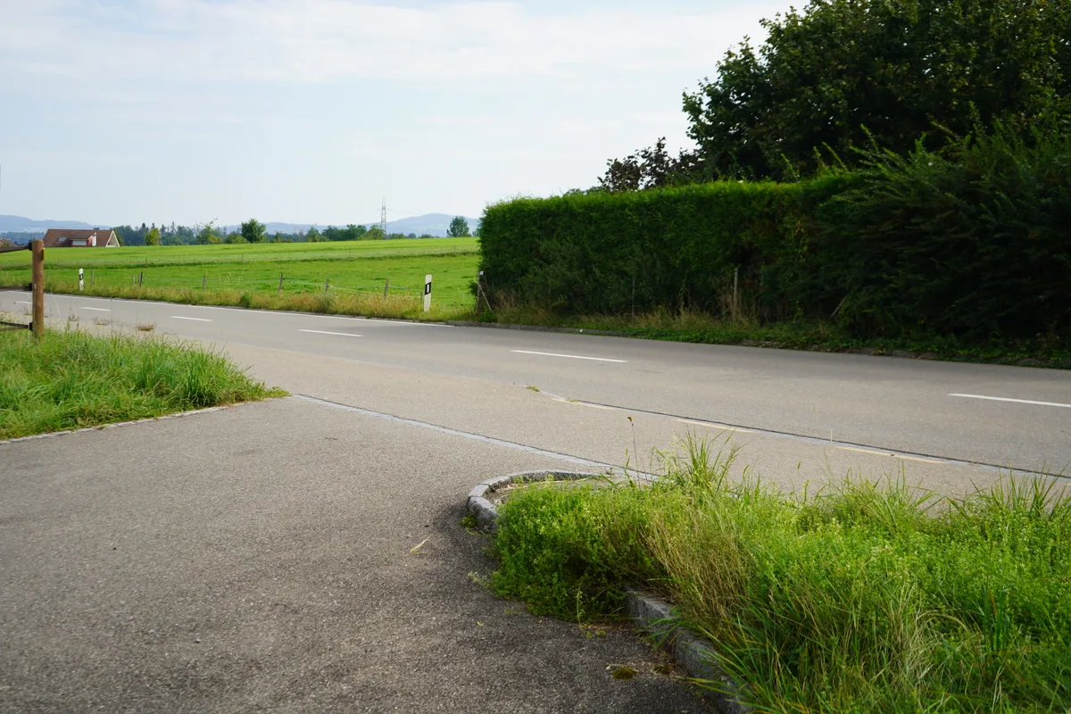 Man sieht die Zufahrt zum Hof von der Hauptstrasse aus.